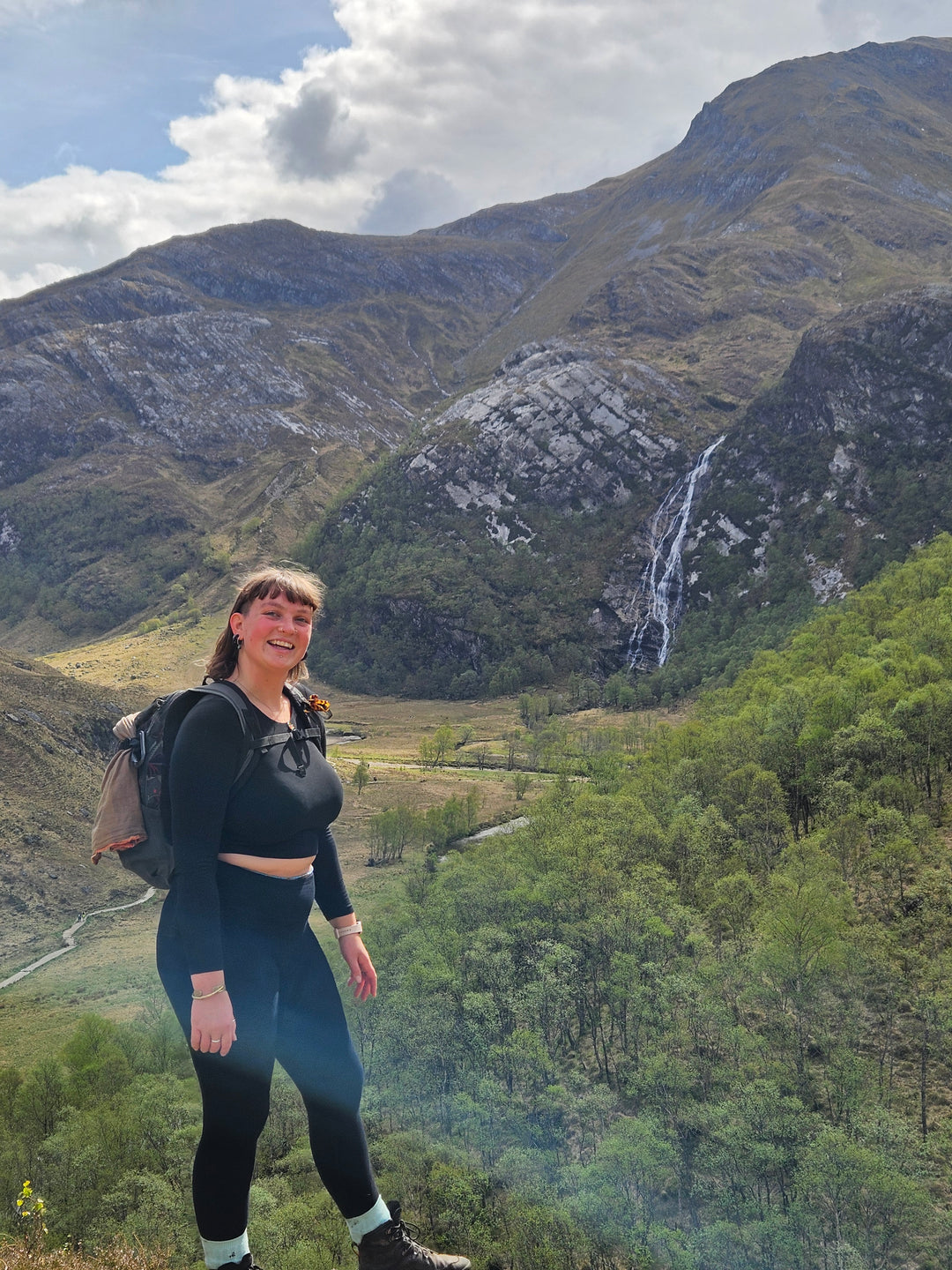 Woman hiking in a mountain valley with a waterfall